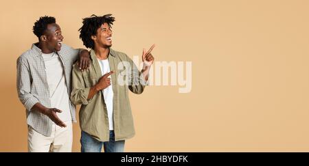 Check This. Two African Guys Looking And Pointing Aside At Copy Space Stock Photo