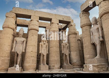 Large statue of Ramses II in ancient egyptian Luxor Temple with columns in courtyard area Stock Photo
