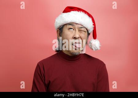 The Asian man portrait with santa claus hat on the pink background. Stock Photo