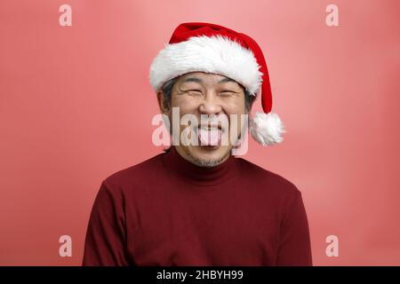 The Asian man portrait with santa claus hat on the pink background. Stock Photo