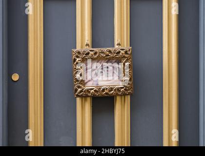 Gold framed open sign hanging on retro vintage door.  Store sign open for business. Grey door and gold leaf ornate frame. Stock Photo