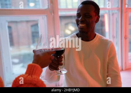 Smiling african man drinking red wine with girlfriend at home, couple enjoy romance in relationships Stock Photo