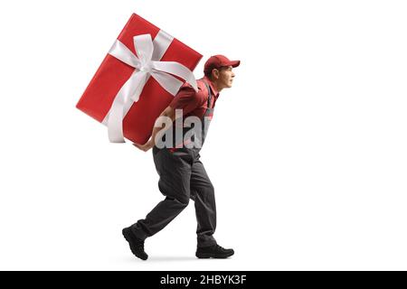 Full length profile shot of a worker in a uniform carrying a big wrapped present on his back isolated on white background Stock Photo