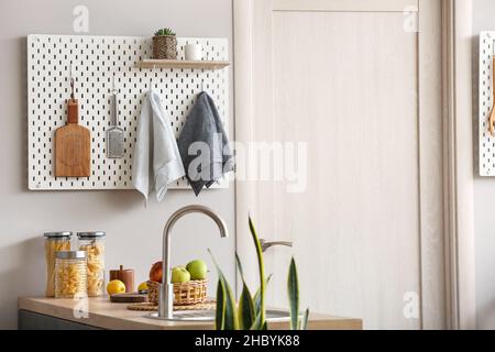 Peg board with kitchenware hanging on light wall Stock Photo