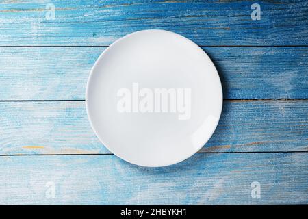 White plate on a blue background top view. Minimalistic concept Stock Photo