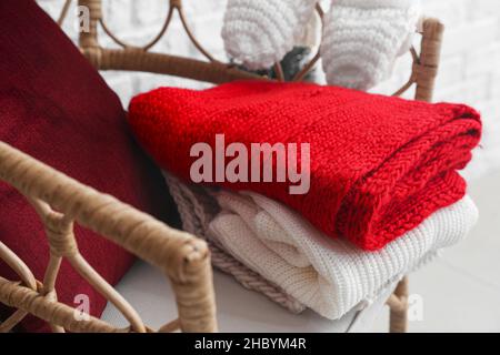 Wicker armchair with winter clothes in room Stock Photo