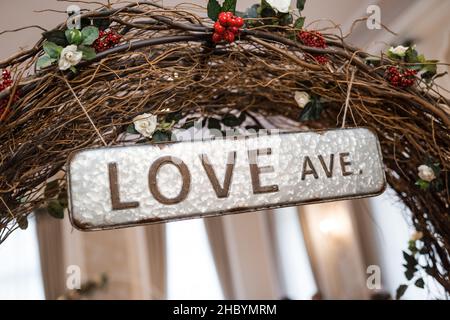 Love Avenue Ave wooden branch archway with metal plate street sign hanging above. Romantic wedding ceremony dressing for couple in love engaged to be Stock Photo