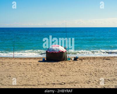 Fuengirola, Malaga, Spain. 10/23/2021. A retired man fishing next to his tent on the shore of Fuengirola beach. Stock Photo