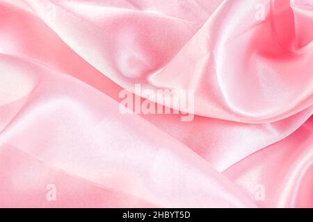 Light pastel pink color silk wavy textile pattern as a smooth textured background. Rose colored soft satin fabric drapery. Stock Photo