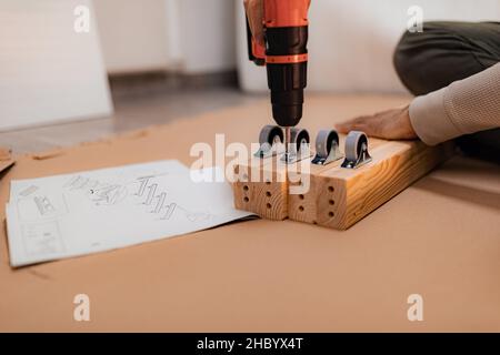 Man working on a new bed installation and using a cordless drill Stock Photo