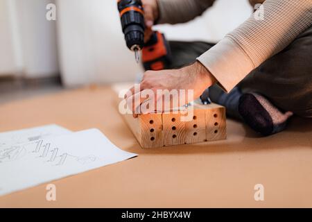 Man working on a new bed installation and using a cordless drill Stock Photo