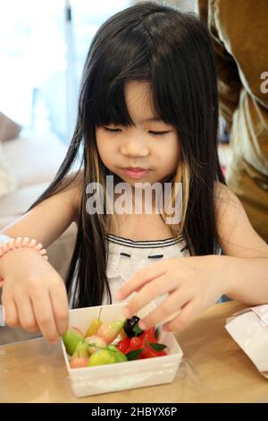 The cute girl eating Thai desserts called Kanom Look Choup. Stock Photo