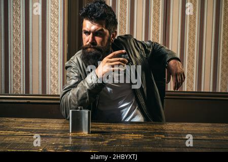 Bearded sman is drinking expensive whisky. Man with beard holds glass brandy. Elegant and stylish man in classical wear holding glass with wiskey. Stock Photo