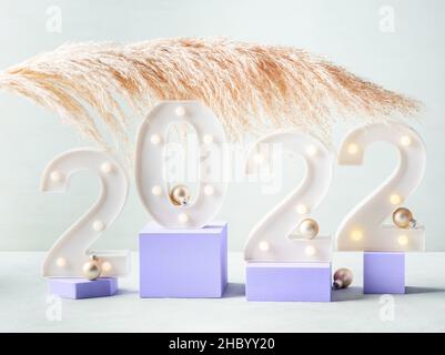 New year 2022 numbers with pampas branch on purple podiums Stock Photo