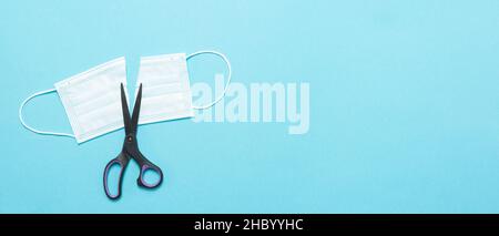 medical mask cut into 2 parts and scissors with space for text. View from above. Stock Photo