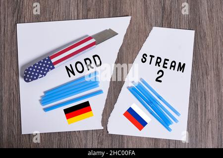 Plastic straws on Russian and German national flags. Nord Stream gas pipeline, sanctions and politics. Russia Vs Germany. Torn paper. Stock Photo