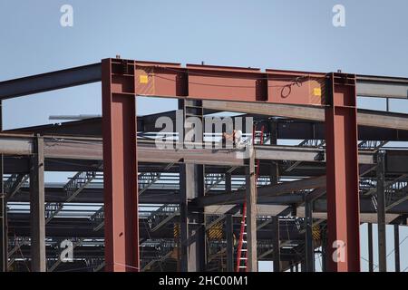 A worker is shown among steel framing at a construction site of a large retail store. Stock Photo