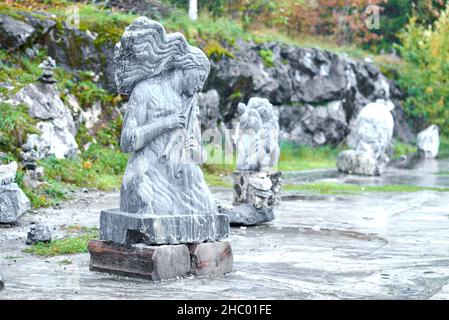 Ruskeala, Russia - 09.14.2021: Marble sculpture of a curly-haired girl playing the flute. Blurred background, art bokeh effect Stock Photo