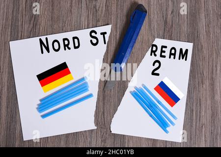 Plastic straws on Russian and German national flags. Nord Stream gas pipeline, sanctions and politics. Russia Vs Germany. Torn paper. Stock Photo