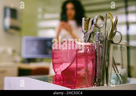 Close up photo of stomatology instruments on the table in a new modern dental clinic office with a dentist woman over the blurred background. Stock Photo