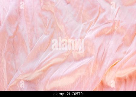 Light pastel pink color wavy nylon and polyamide textile pattern as a smooth textured background. Pale rose colored soft fabric drapery. Stock Photo