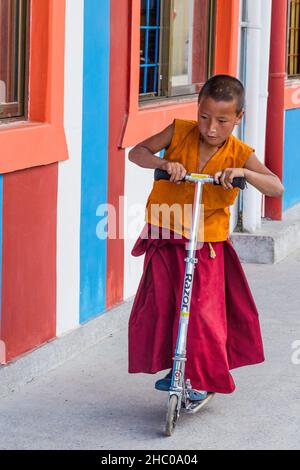 A young Buddhist monk riding a scooter at the Pema Tsal Sakya Monastery near Pokhara, Nepal. Stock Photo