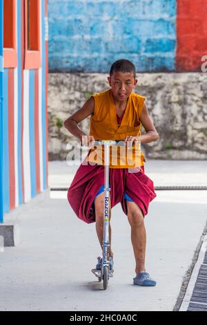 A young Buddhist monk riding a scooter at the Pema Tsal Sakya Monastery near Pokhara, Nepal. Stock Photo