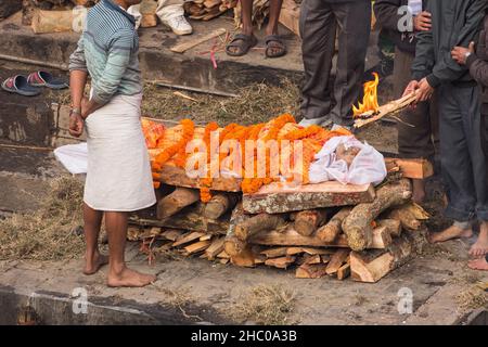 The lead mourner lights the mouth of the deceased in the cremation ceremony at Pashupatinath, Kathmandu, Nepal. Stock Photo