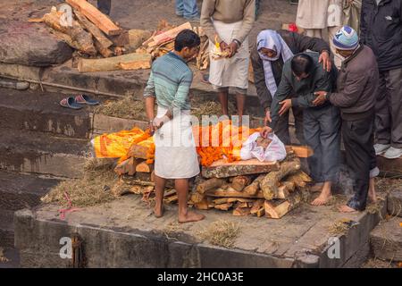 The lead mourner puts rice in the mouth of the deceased in the cremation ceremony at Pashupatinath, Kathmandu, Nepal. Stock Photo