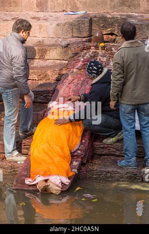 The feet of the deceased are ritually washed in the Bagmati River prior to cremation.  Pashupatinath, Kathmandu, Nepal. Stock Photo