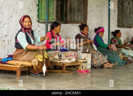 Tibetan refugee women spin wool into yarn by hand for making rugs in a refugee settlement in Pokhara, Nepal. Stock Photo