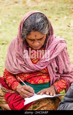 An older Nepali woman learning to read and write near the Himalayan foothill village of Dhampus, Nepal. Stock Photo