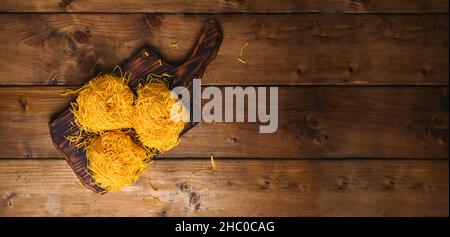 Fresh Tagliatelle pasta . Traditional Italian named Angel Hair . capellini d'angels. Woman cooking Italian egg pasta, homemade and fresh in flour on a cutting table. Banner. Long format. Copy space Stock Photo