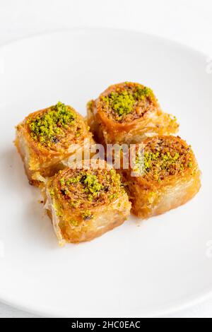 Pistachio baklava dessert on a white background. Turkish sweet dessert concept. plate of pistachio baklava. sherbet sweet Mediterranean bakery. close Stock Photo