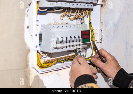 An electrician install an electrical panel in the house. Conducting electricity, switching on and protecting. Stock Photo