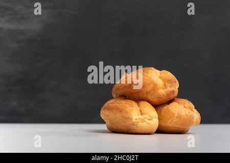 Profiteroles or popovers, eclairs side view. Three appetizing profiteroles. Gray background Stock Photo