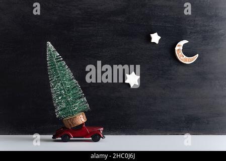 Small tree on model car, black background. Round-the-clock delivery for the new year. Stock Photo