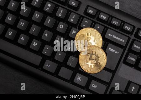Two gold Bitcoins on computer keyboard close up. Electronic virtual money. Mining cryptocurrency concept Stock Photo