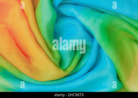 Multicolored soft silk fabric texture in spiral shape closeup, abstract background Stock Photo