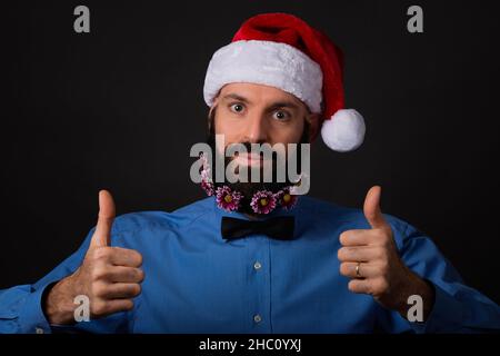 Christmas, holidays, barbershop and style concept - handsome bearded santa claus man with small flowers in long beard showing ok sign with both hands Stock Photo