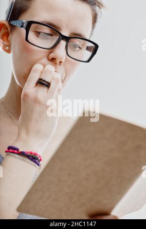 Anxious woman biting her nails as she looks at a journal or diary in a close up low angle cropped image on white Stock Photo