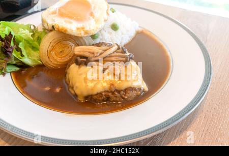 Japanese Pork Burger menu, close up Japanese Burger and curry with white rice, topped with cheese, Shimeji mushroom, fried egg. Food in white round pl Stock Photo