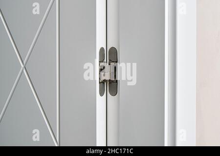 Elegant white contemporary door with rhombus pattern decor fastened with hinge installed in light room at restoration extreme closeup Stock Photo