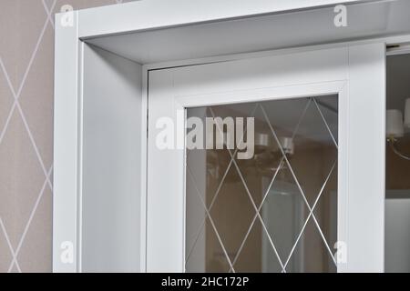 Elegant trendy inner doors with rhombus pattern on glass surface and silver handles in light spacious room of renovated apartment closeup Stock Photo