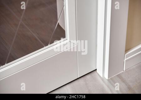 Elegant trendy inner doors with rhombus pattern on glass surface and silver handles in light spacious room of renovated apartment closeup Stock Photo
