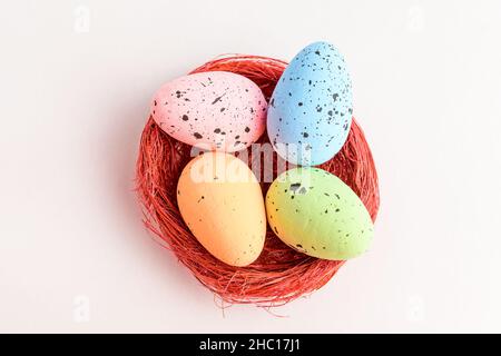Mixed colored decorative red Easter eggs in a red rustic basket isolated on a white table Stock Photo