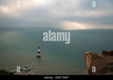 Sunlight breaking through the thick December clouds over Beachy Head lighthouse on the East Sussex coast, south east England Stock Photo