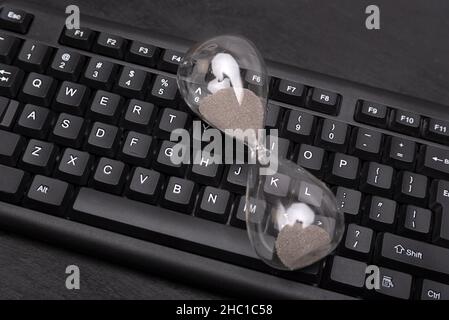 Hourglass on computer keyboard. Time management concept. Urgency and outcome of time Stock Photo
