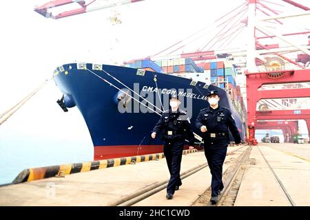 QINGDAO, CHINA - DECEMBER 23, 2021 - Police officers patrol beside cargo ships at the Huangdao Border Control Station of Qingdao Container Terminal in Stock Photo