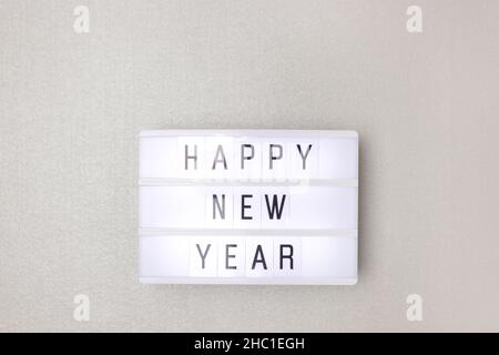 Happy New Year. White lightbox with phrase on a silver background with copy space. Stock Photo
